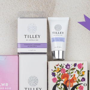 A flat lay of The Hamper Boutique Co's Relax and Rejuvenate Tea Hamper, featuring soy wax melts and hand & nail cream, displayed among decorative boxes, including one adorned with a squirrel and floral design.