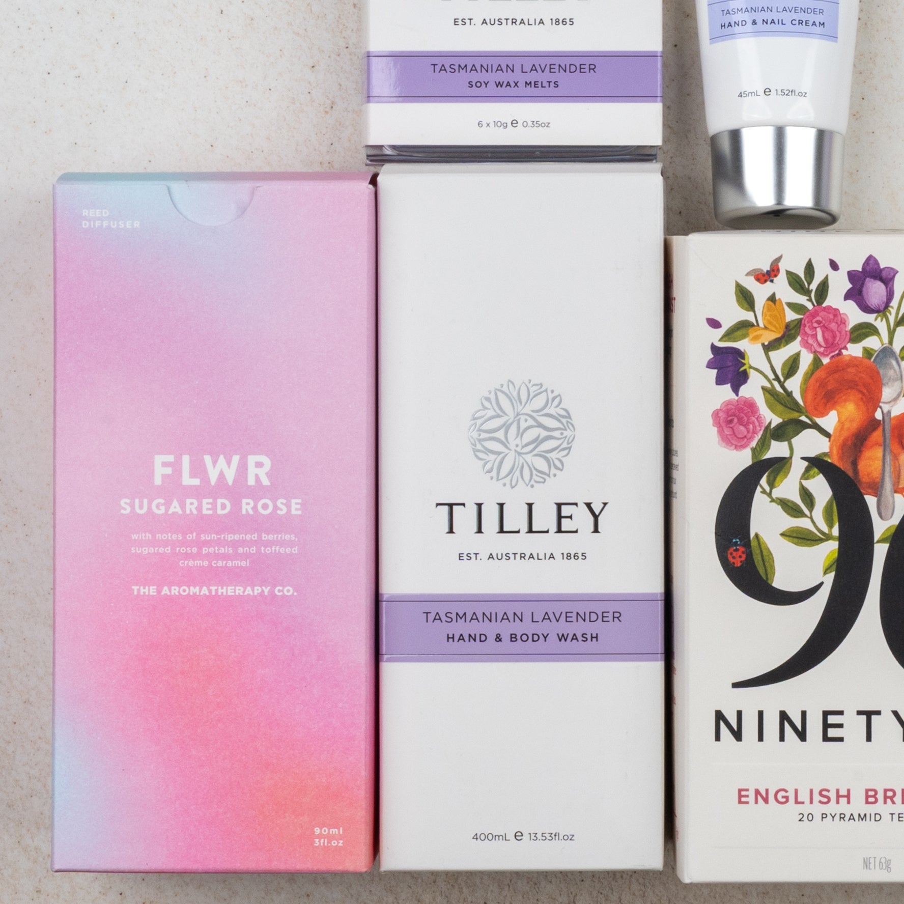 A flat lay featuring The Hamper Boutique Co's Relax and Rejuvenate Tea Hamper with bath and body treats, tea, and lavender-scented products for a soothing experience.