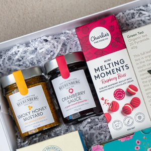 The Hamper Boutique Co Sweet Indulgence Tea Hamper features Beerenberg Smoky Honey Mustard, Beerenberg Cranberry Sauce, and Charlies Raspberry Bliss Melting Moments, beautifully presented on white shredded paper.