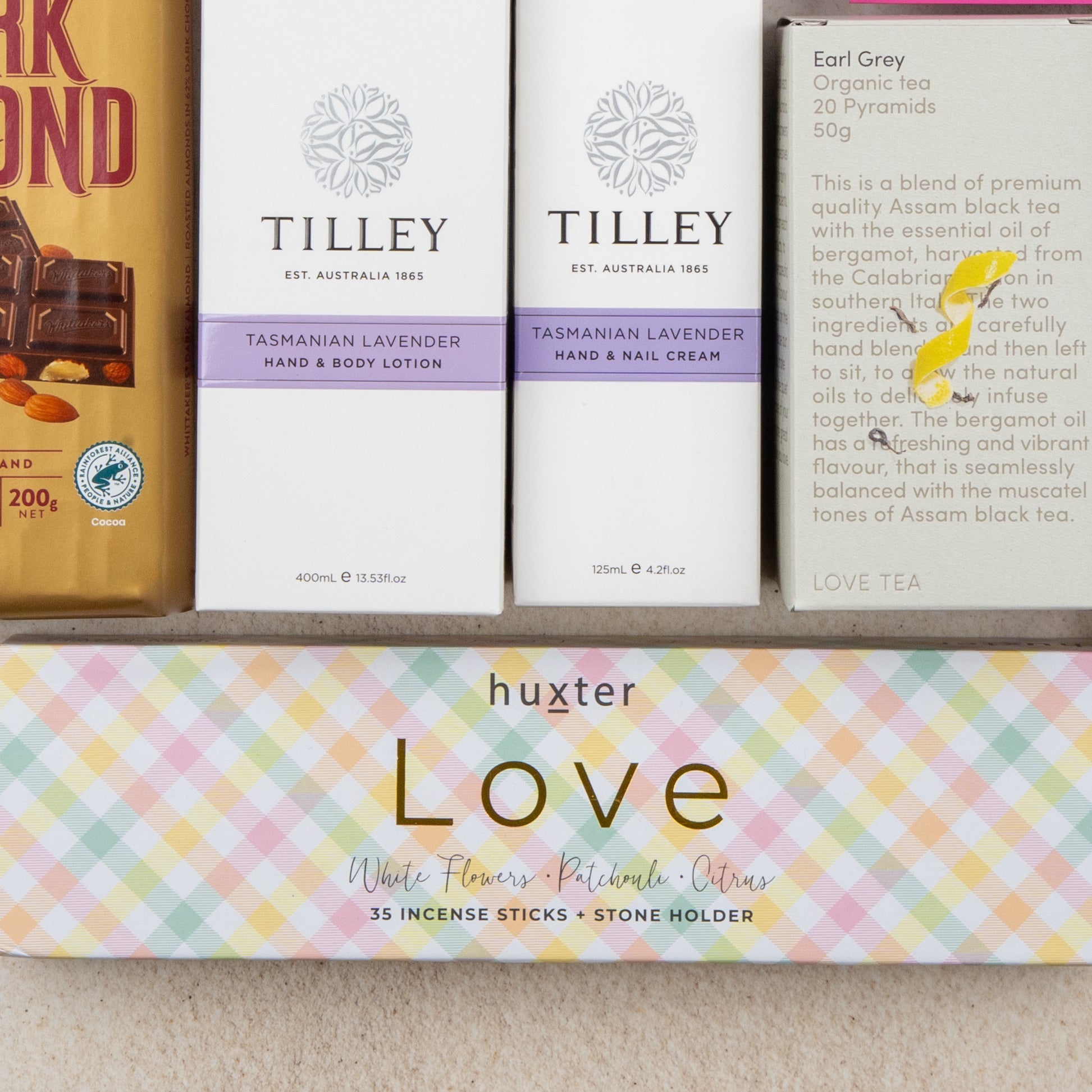 The Hamper Boutique Co’s Rejuvenation and Wellness Hamper includes dark almond chocolate, lavender hand and body lotion, hand and nail cream, Earl Grey organic tea, and Huxter Love incense sticks in a colorful box.