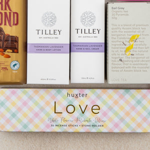The Hamper Boutique Co’s Rejuvenation and Wellness Hamper includes dark almond chocolate, lavender hand and body lotion, hand and nail cream, Earl Grey organic tea, and Huxter Love incense sticks in a colorful box.