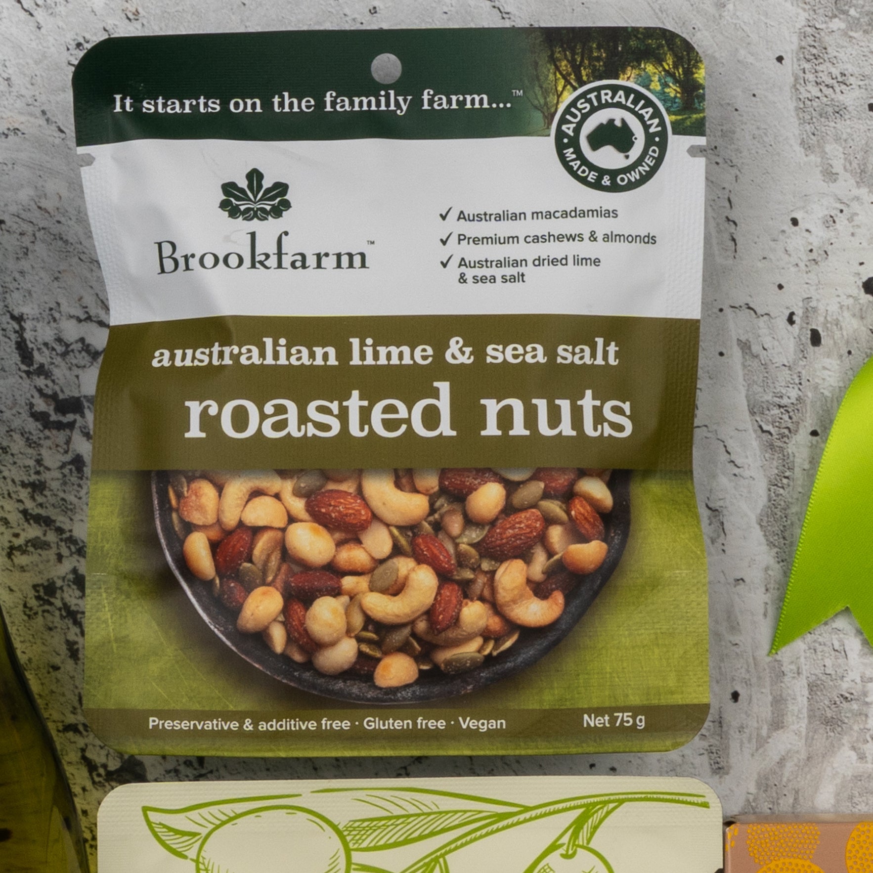 A Gourmet Treats Gift Hamper by The Hamper Boutique Co, featuring a bowl of mixed nuts on the front. The package highlights that the product is vegan, gluten-free, and preservative-free.