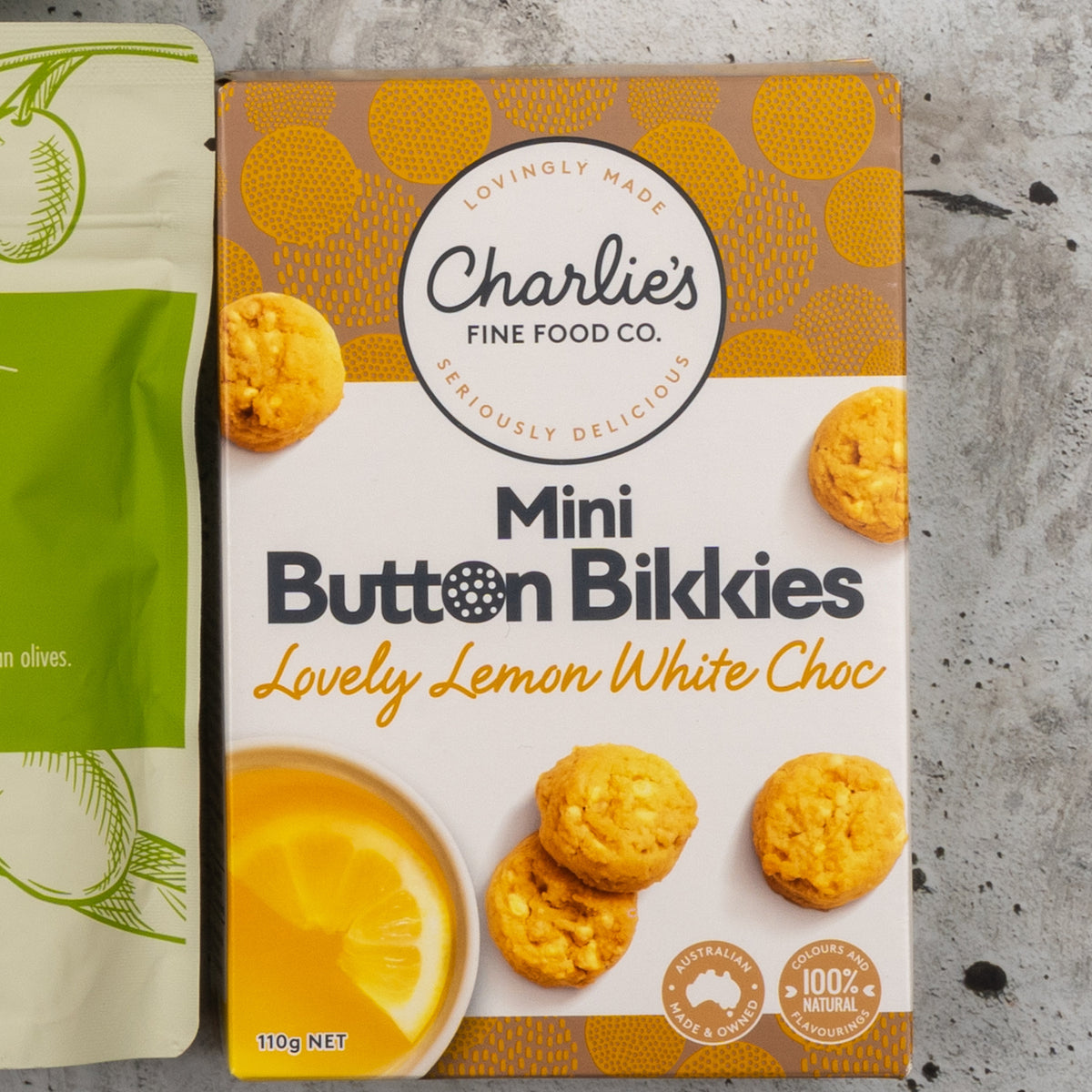 Gourmet Treats Gift Hamper: Charlie's Lovely Lemon bikkies box beside the olives