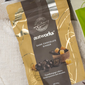 A Gourmet Indulgence Hamper from The Hamper Boutique Co, in gold and dark brown packaging with white text, features an image of chocolate-coated ginger pieces and diced ginger in a bowl on the front.