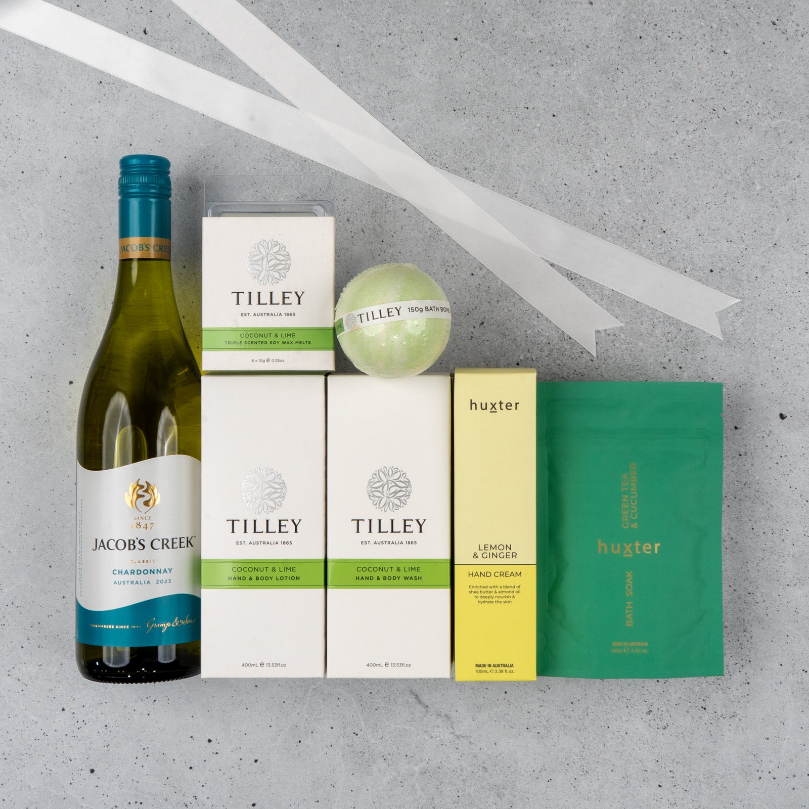 The Hamper Boutique Co’s “White Wine and Self-Care” hamper features premium skincare and wine items arranged on a gray surface with white ribbons.