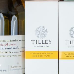 Close-up of the Chardonnay and Self-Care Hamper by The Hamper Boutique Co, featuring two Tilley Tahitian Frangipani hand and body wash bottles beside partially visible wine bottles labeled chardonnay and Marlborough.