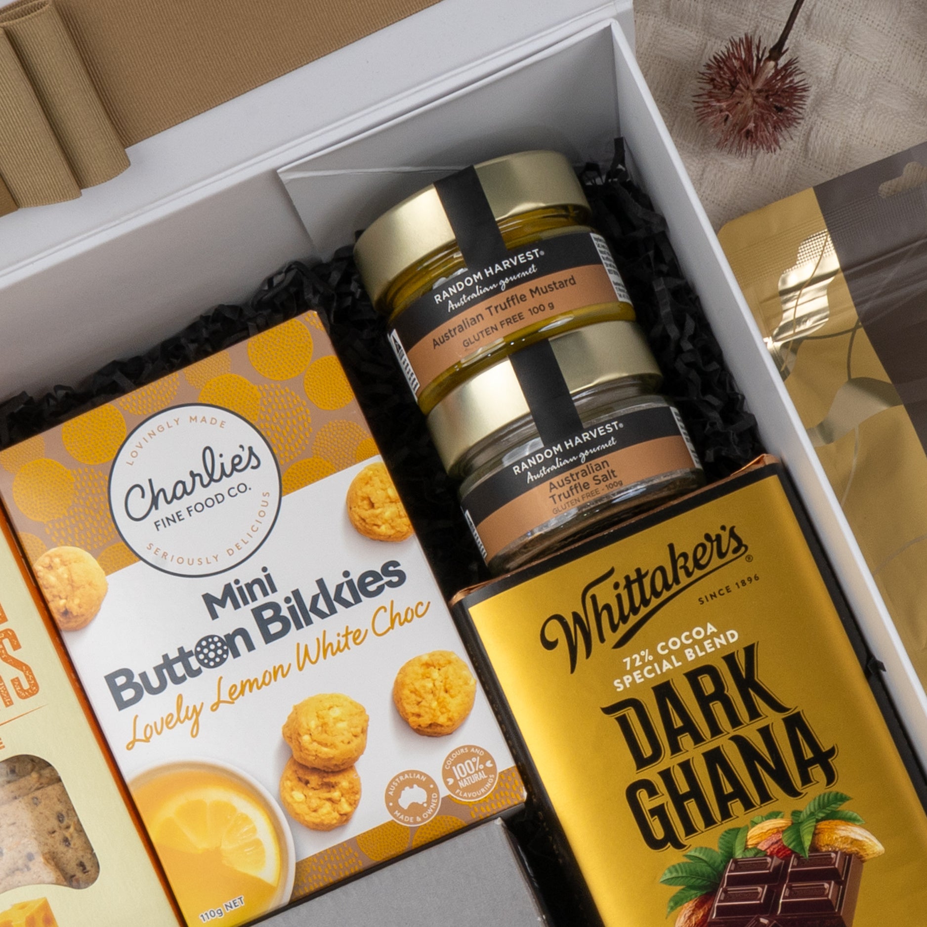 The Hamper Boutique Co’s Ultimate Gourmet Collection Hamper features Charlies Mini Butter Bikkies, Random Harvest truffle mustards, and a Whittaker’s Dark Ghana chocolate bar, all presented with elegant black packing.