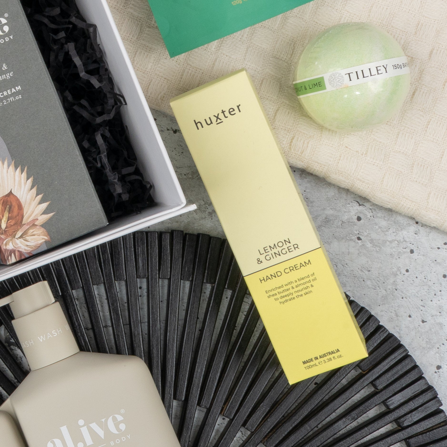 A flat lay of The Hamper Boutique Co's Elegance and Self-Care Gift Hamper, featuring premium bath products arranged on a black mat and textured surface.