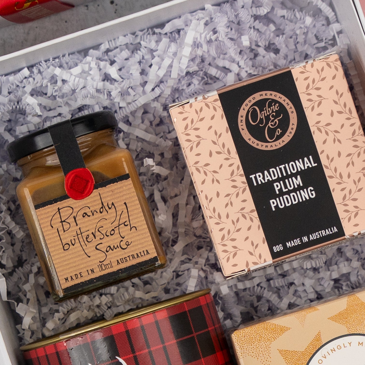 The Sweet Traditions gift box by The Hamper Boutique Co includes Brandy Butterscotch Sauce and Traditional Plum Pudding, both made in Australia, and comes packed with shredded white paper.