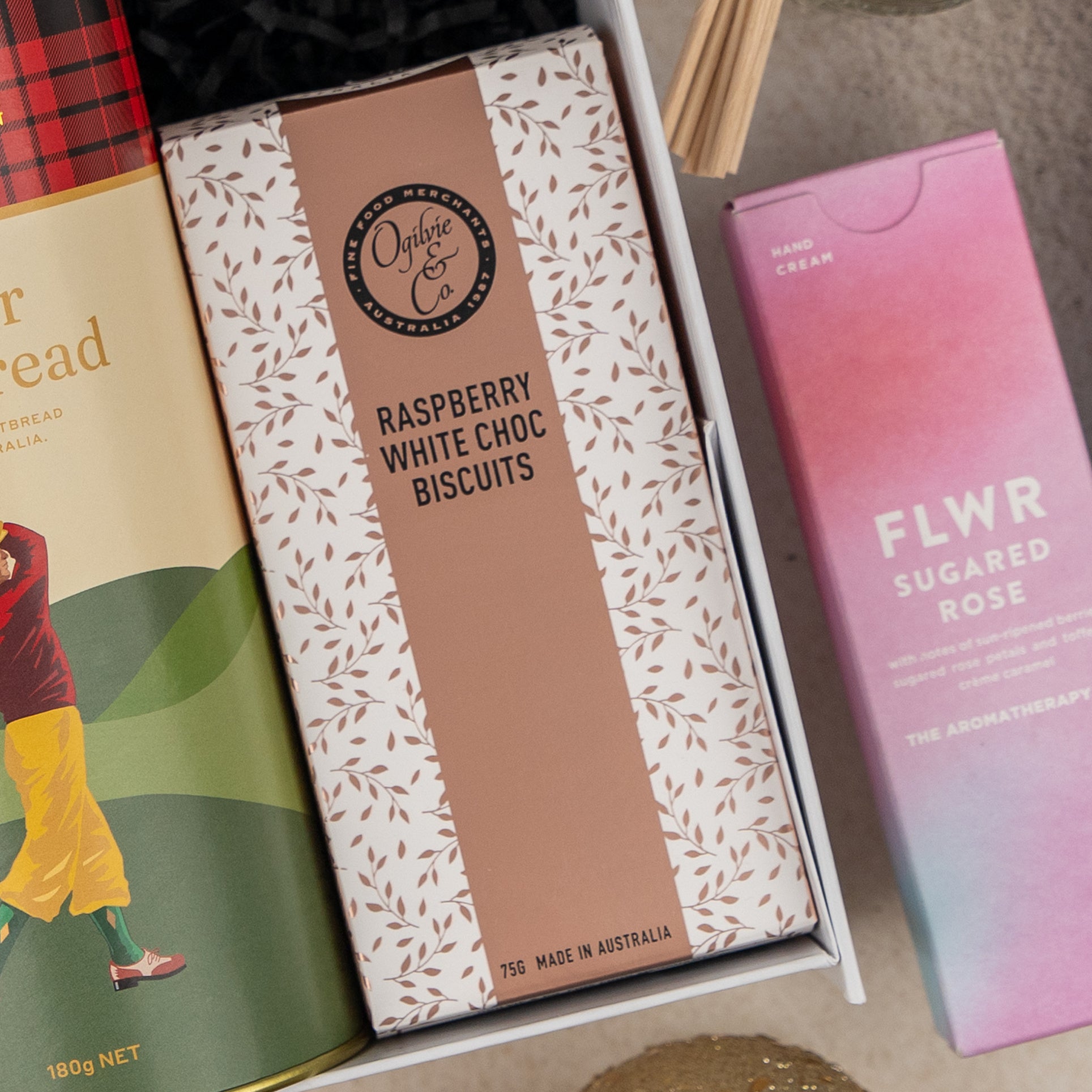 The Hamper Boutique Co’s Sparkling Comfort & Joy includes raspberry white choc biscuits, FLWR sugared rose hand cream, and a stylishly patterned gift package.