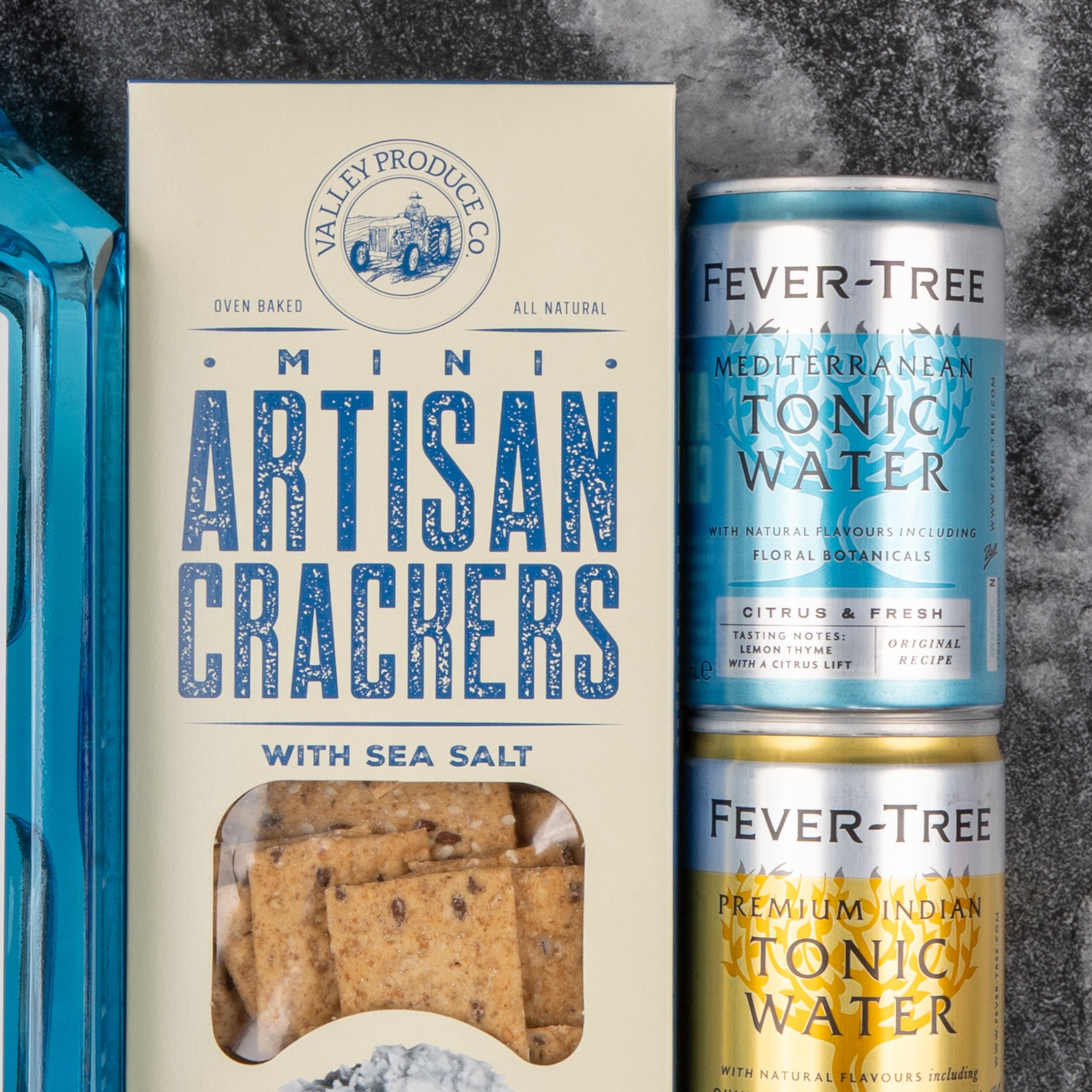 A Bombay Sapphire Gin and Tonic Hamper by The Hamper Boutique Co is displayed on a dark textured surface.