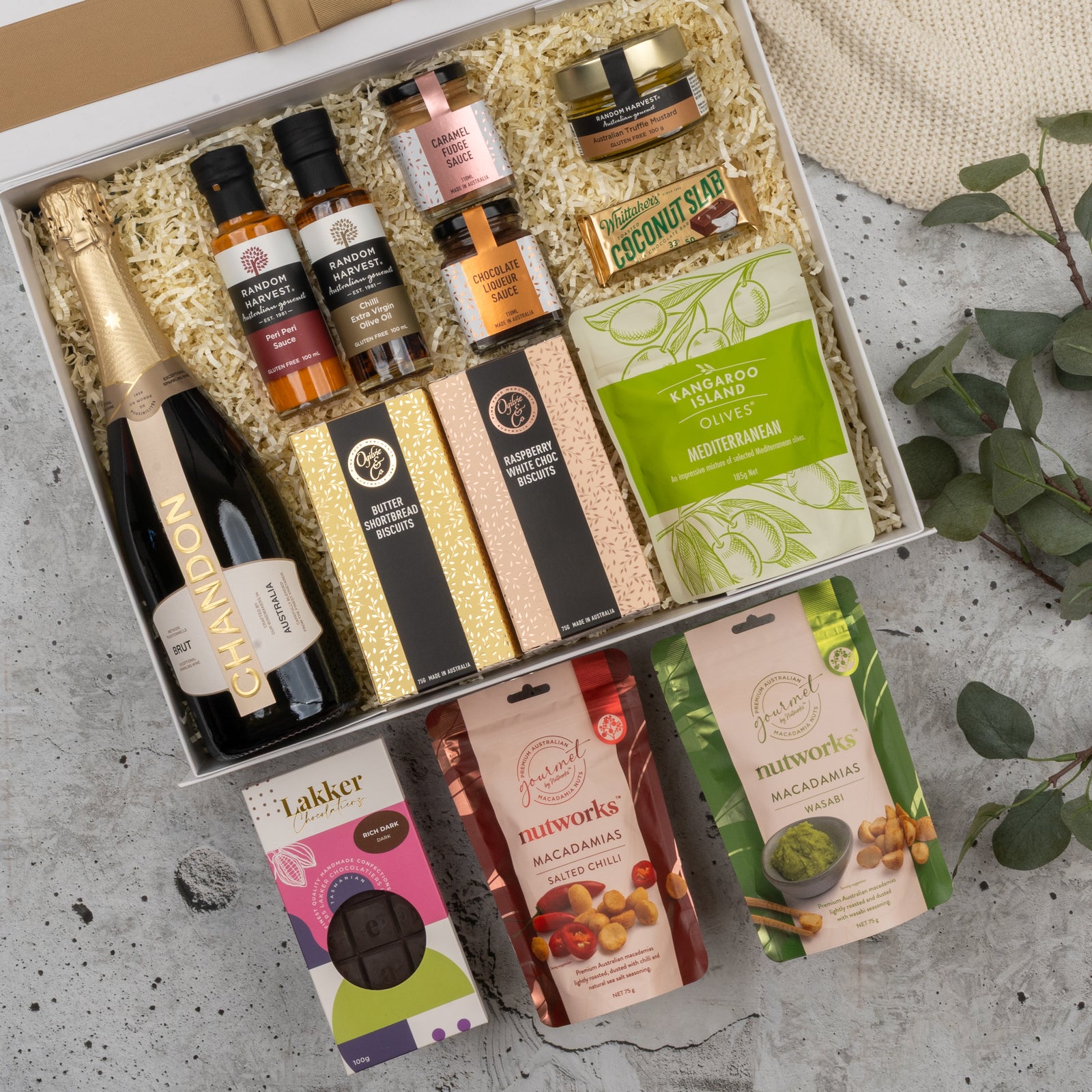The Hamper Boutique Co’s Chandon Gourmet Celebration Hamper features Chandon sparkling wine, assorted snacks, chocolates, crackers, dips, olives, and condiments—all beautifully presented with eucalyptus accents.