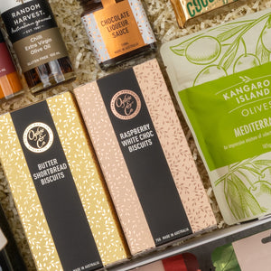 The Hamper Boutique Co's Chandon Gourmet Celebration Hamper features butter shortbread, raspberry white choc biscuits, chocolate liqueur sauce, olive oil, and Mediterranean olives on decorative shred.